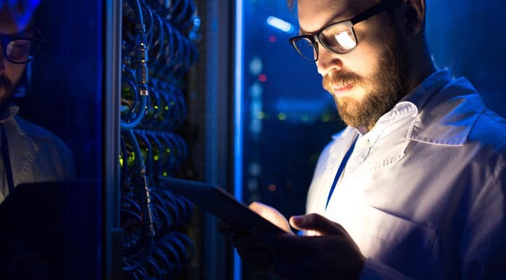 Smart computer engineer using laptop in server room