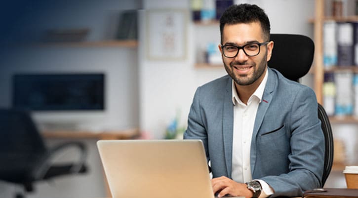 Portrait of a handsome young businessman working in office at a desk in frnt of his laptop